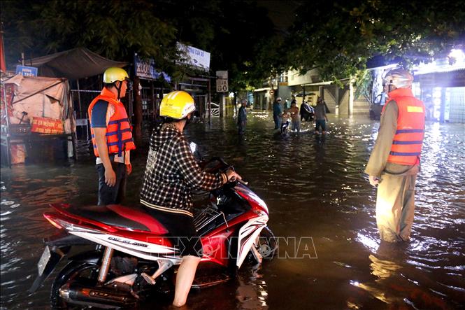 Lực lượng dân quân tự vệ phường Bình Thuận túc trực tại tuyến đường Lê Thị Hồng Gấm để hỗ trợ người dân qua khu vực ngập sâu. Ảnh: Nguyễn Thanh – TTXVN