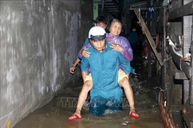 Hỗ trợ người già di chuyển khỏi khu vực ngập sâu đến nơi an toàn. Ảnh: Nguyễn Thanh - TTXVN