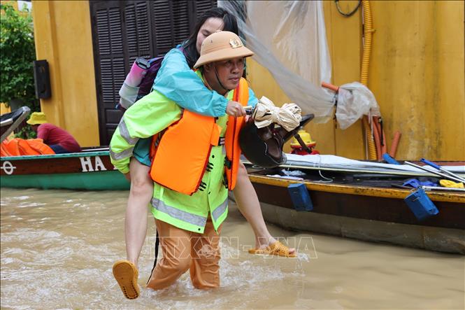 A local policeman carries a tourist to safe grounds in Da Nang. VNA Photo