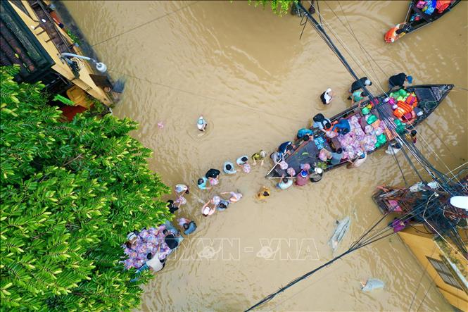 Chính quyền và người dân chung tay vận chuyển tiếp ứng lương thực cho các hộ dân trong vùng ngập nước. Ảnh: Trần Lê Lâm - TTXVN 