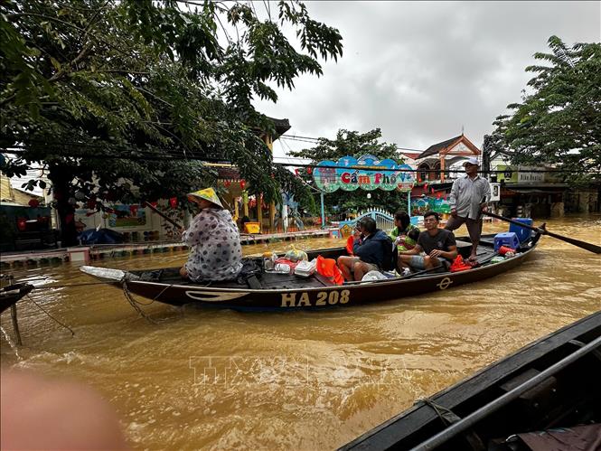 Người dân Hội An mang thực phẩm về cho gia đình đang trong khu vực ngập nước. Ảnh: Trần Lê Lâm - TTXVN