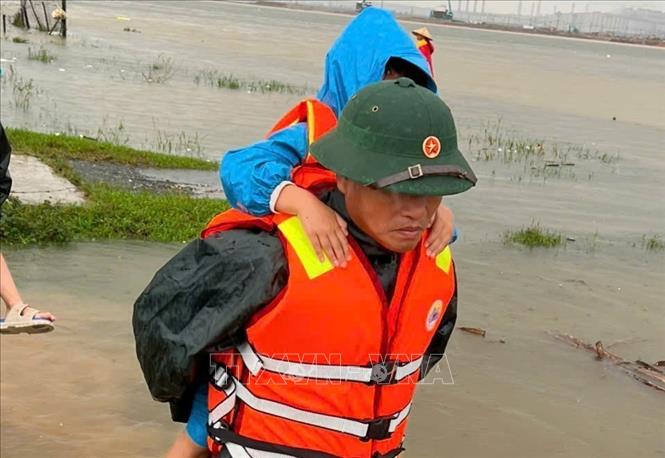 Bộ đội biên phòng hỗ trợ di dời người dân đến nơi tránh trú. Ảnh: Hoàng Ngà - TTXVN