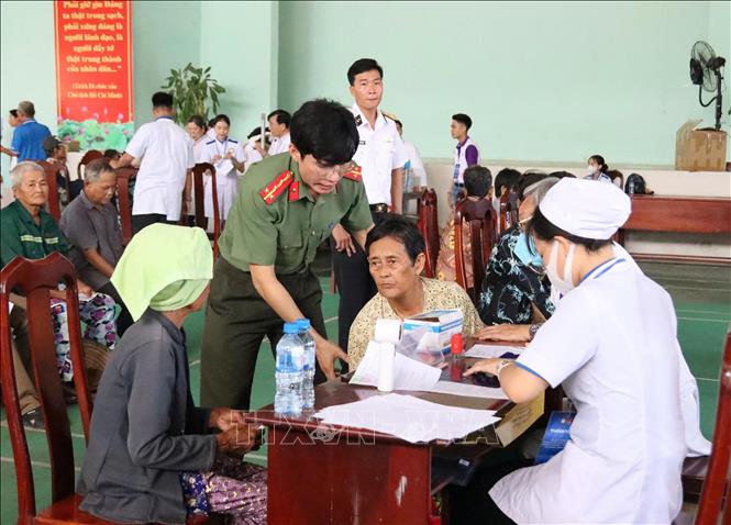 Cán bộ, chiến sĩ Công an An Giang hỗ trợ người lớn tuổi đến khám bệnh và cấp thuốc miễn phí. Ảnh: Văn Sĩ - TTXVN