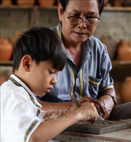 Teaching generations in the family has always been the duty of the Cham people who live and maintain the Bau Truc pottery craft. VNA Photo: Nhật Anh