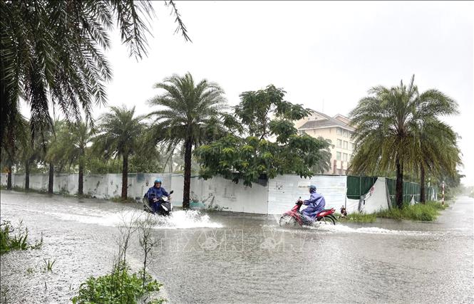 Các phương tiện xe máy di chuyển khó khăn khi qua các điểm ngập lụt trên địa bàn phường Đồng Hới, tỉnh Quảng Trị. Ảnh: Võ Dung - TTXVN