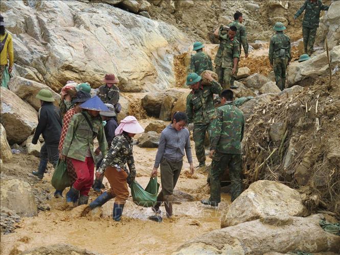 Người dân cùng các cán bộ, chiến sĩ Quân đoàn 34 triển khai công tác mở đường vào 5 thôn ở xã Ngọc Linh (Quảng Ngãi) bị cô lập do mưa lũ. Ảnh: Dư Toán – TTXVN