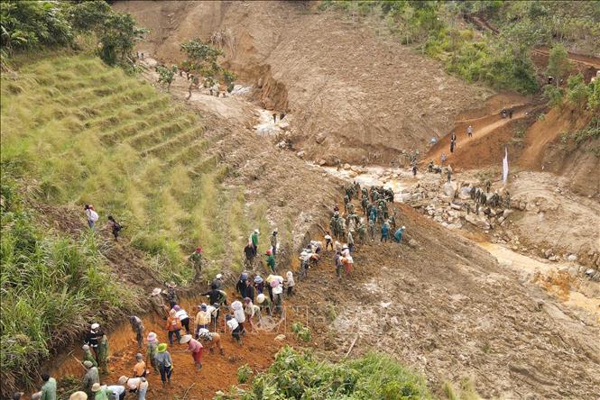 Người dân cùng các cán bộ, chiến sĩ Quân đoàn 34 triển khai công tác mở đường vào 5 thôn ở xã Ngọc Linh (Quảng Ngãi) bị cô lập do mưa lũ. Ảnh: Dư Toán – TTXVN