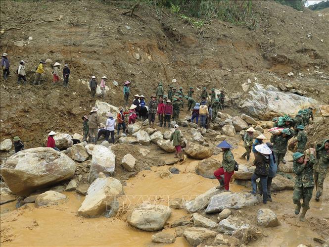 Người dân cùng các cán bộ, chiến sĩ Quân đoàn 34 triển khai công tác mở đường vào 5 thôn ở xã Ngọc Linh (Quảng Ngãi) bị cô lập do mưa lũ. Ảnh: Dư Toán – TTXVN
