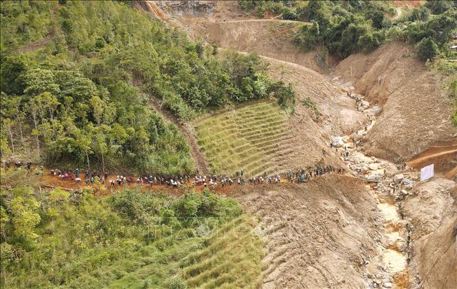 Người dân cùng các cán bộ, chiến sĩ Quân đoàn 34 triển khai công tác mở đường vào 5 thôn ở xã Ngọc Linh (Quảng Ngãi) bị cô lập do mưa lũ. Ảnh: Dư Toán – TTXVN