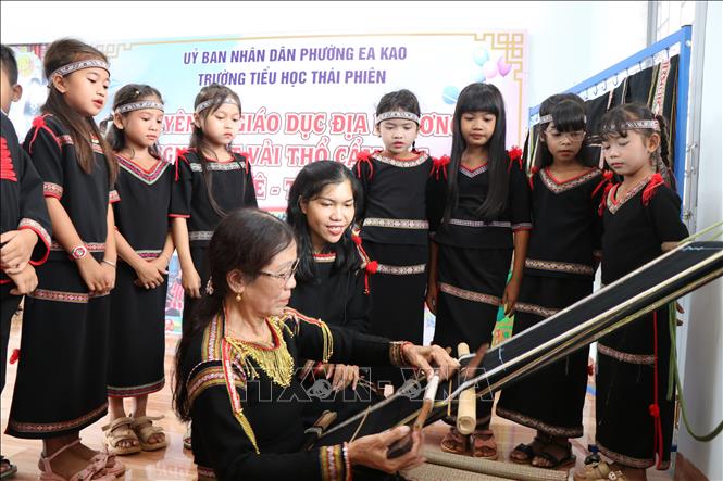 Nghệ nhân H’Đer Buôn Krông (buôn H’Đơk, phường Ea Kao, tỉnh Đắk Lắk), người có hơn 20 năm gắn bó với nghề dệt, hướng dẫn cho học sinh tìm hiểu về cách dệt vải thổ cẩm. Ảnh: Nguyên Dung - TTXVN