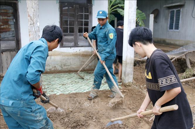 Thanh niên, tình nguyện viên hỗ trợ người dân thôn 2, xã Tuy Phong (Lâm Đồng) cào xúc bùn đất, vệ sinh nhà cửa. Ảnh: Nguyễn Thanh - TTXVN 