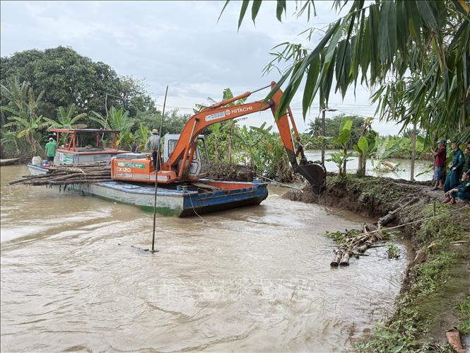 UBND phường Bình Thủy huy động phương tiện gia cố, khắc phục tạm thời đoạn đê bao bị vỡ. Ảnh: Thanh Liêm - TTXVN