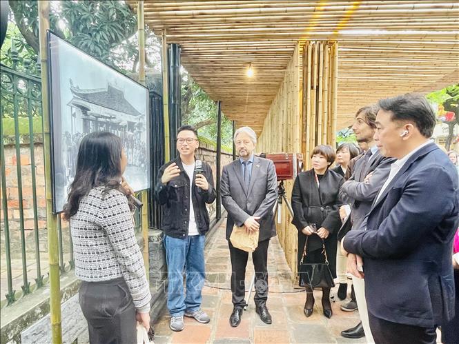 Các đại biểu tham quan triển lãm ảnh và nghe giới thiệu về các tác phẩm. Ảnh: Tuyết Mai - TTXVN 