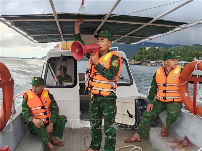 Cán bộ, chiến sĩ sử dụng ca nô tuyên truyền, vận động ngư dân di chuyển người và phương tiện vào nơi trú ẩn an toàn trước khi bão số 13 đổ bộ. Ảnh: TTXVN phát