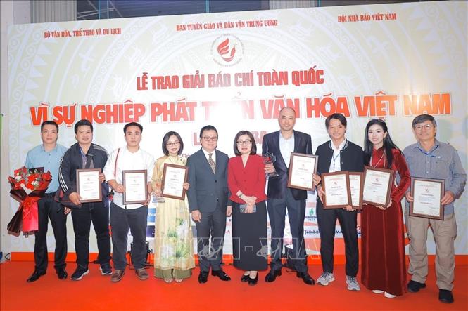 Chủ tịch Hội nhà báo Việt Nam, Phó Trưởng ban Tuyên giáo và Dân vận, Tổng Biên tập Báo Nhân dân Lê Quốc Minh và Phó Tổng Giám đốc TTXVN Đoàn Thị Tuyết Nhung (áo đỏ) chụp ảnh chung với tác giả, nhóm tác giả đoạt giải của TTXVN. Ảnh: TTXVN