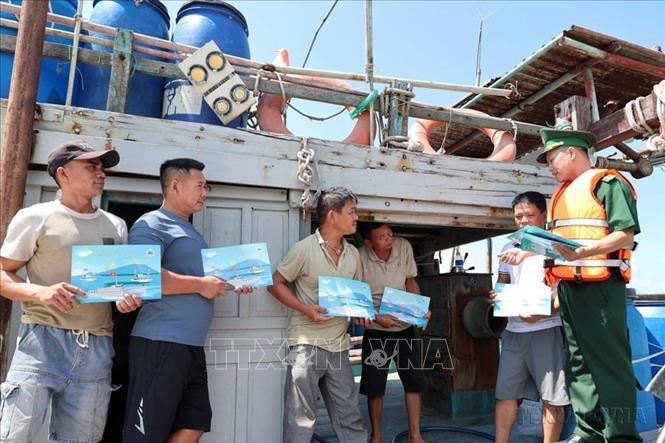 Cán bộ, chiến sĩ Đồn Biên phòng Sơn Trà (BĐBP thành phố Đà Nẵng) tuyên truyền về IUU cho bà con ngư dân trên tàu cá ngoại tỉnh vào neo đậu tránh bão tại cửa biển thành phố (2025). Ảnh: Đỗ Trưởng – TTXVN