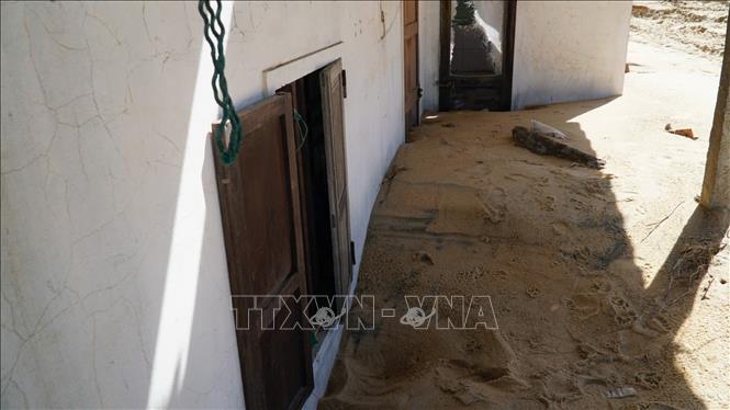 Cát vùi lấp gần một nửa ngôi nhà của người dân làng chài dưới chân cầu Đề Gi. Ảnh: Sỹ Thắng - TTXVN