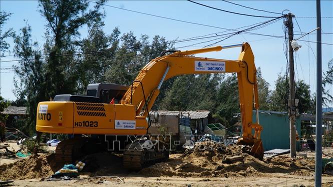 Người dân sử dụng cần cẩu để múc cát cứu tài sản bị cát vùi lấp. Ảnh: Sỹ Thắng - TTXVN 