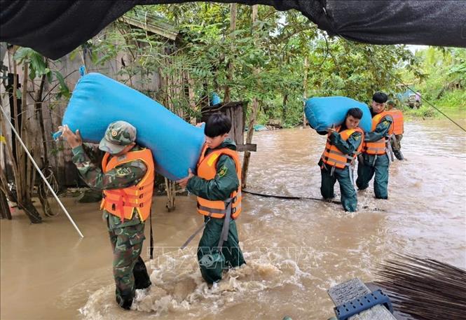 Lực lượng chức năng giúp dân di dời tài sản. Ảnh: TTXVN phát