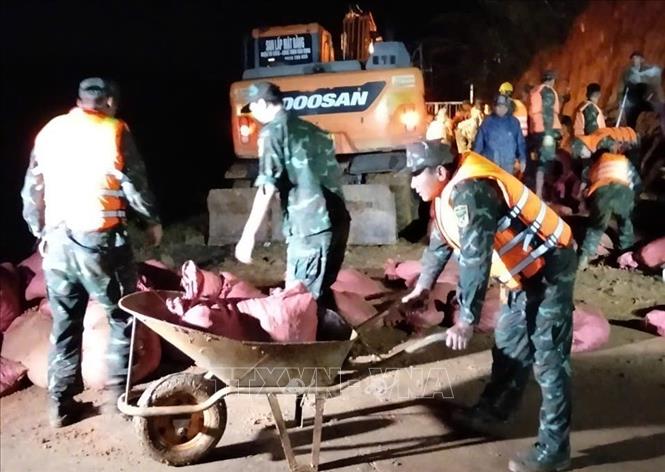 Hàng trăm người gồm bộ đội, dân quân, công an, địa phương được huy động triển khai gia cố hồ thủy lợi Cay An trong đêm 7/11. Ảnh: TTXVN phát