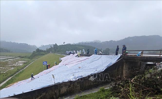 Lực lượng chức năng gia cố tạm thời khu vực đập chính của hồ Cay An trước nguy cơ vỡ do lượng nước về tăng nhanh. Ảnh: TTXVN phát