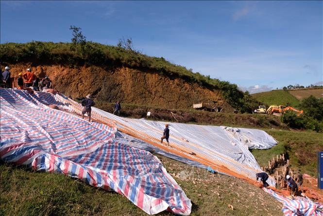 Hàng chục người và phương tiện vẫn tiếp tục triển khai các biện pháp gia cố phần thân đập của hồ thủy lợi Cay An (xã Tà Năng, Lâm Đồng) trong sáng 8/11. Ảnh: Nguyễn Dũng – TTXVN 