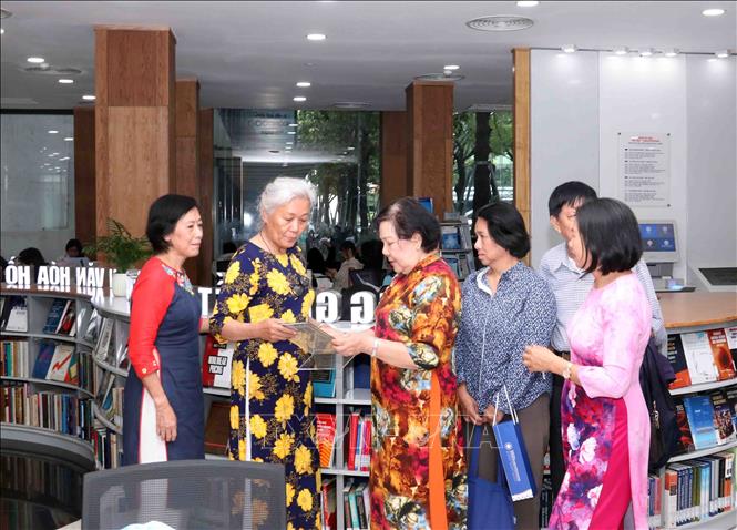 Đại diện gia đình cố Giáo sư Trần Hữu Dũng xem những cuốn sách của cố giáo sư Trần Hữu Dũng tại các kệ sách trung tâm trong Thư viện do cố giáo sư Trần Hữu Dũng tặng trường Đại học Công thương Thành phố Hồ Chí Minh. Ảnh: Xuân Khu-TTXVN