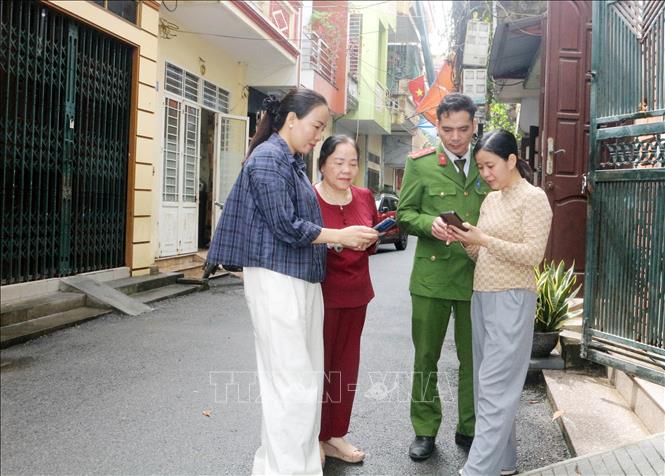 Tổ công nghệ số cộng đồng cùng cán bộ công an phường Phủ Lý đến từng khu dân cư hướng dẫn người dân tham gia góp ý dự thảo các văn kiện Đại hội XIV của Đảng thông qua ứng dụng VNeID. Ảnh: Nguyễn Chinh – TTXVN