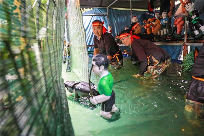 Các nghệ nhân đứng trong buồng trò (thủy đình) được che chắn kỹ lưỡng, sử dụng sào, dây và bộ máy điều khiển ẩn dưới mặt nước để làm cho con rối cử động, di chuyển một cách sống động như thật. Ảnh: Khánh Hoà - TTXVN