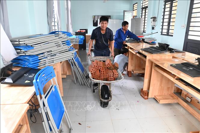 Giáo viên, nhân viên bảo vệ Trường Tiểu học Phước Bình B (cơ sở IV), xã Phước Chỉ, tỉnh Tây Ninh chuyển gạch vào kê những dãy bàn gỗ lên khỏi mặt nước để tránh hư hỏng. Ảnh: Minh Phú - TTXVN