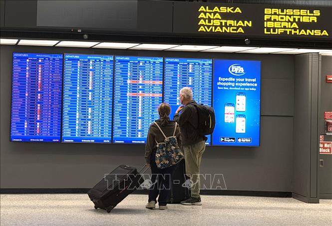 Hành khách xem bảng thông tin chuyến bay khởi hành tại Sân bay quốc tế Washington Dulles, bang Virginia, tối 8/11/2025 (giờ địa phương). Ảnh: Ngọc Quang - PV TTXVN tại Mỹ.