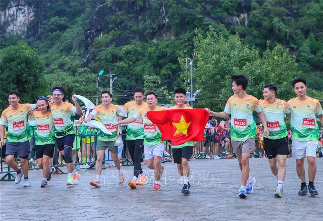 Các vận động viên chạy về đích cùng lá cờ Tổ quốc. Ảnh: Công Luật - TTXVN