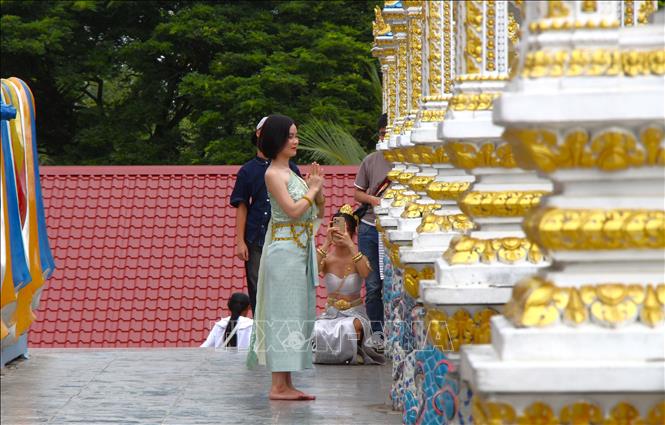 Visitors in traditional Khmer attire take photos at the pagoda. Photo: Nguyen Hang – VNA