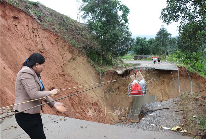 Người dân sử dụng cáp vận chuyển thực phẩm qua điểm sạt lở bị đứt gãy 40m mặt đường trên tuyến đường ĐH83 đoạn Km8+200 qua thôn Tà Vinh, xã Sơn Tây Hạ. Ảnh: Phạm Cường-TTXVN