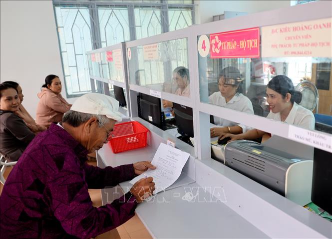 Cán bộ xã Phước Hữu (Khánh Hòa) hướng dẫn người dân thực hiện thủ tục hành chính trực tuyến tại Bộ phận một cửa. Ảnh: Nhật Anh - TTXVN