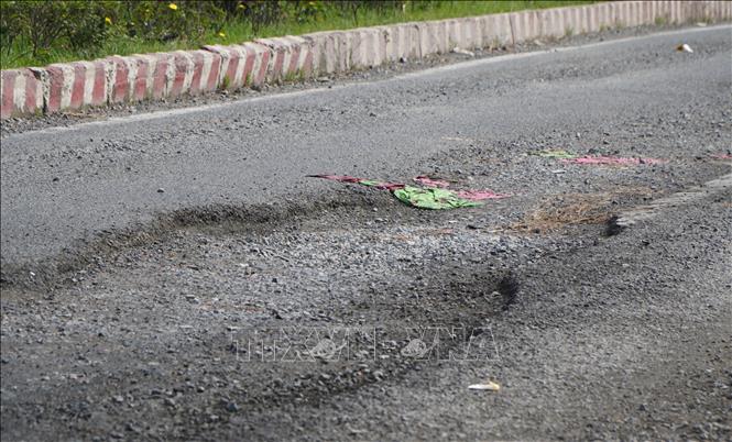 Mặt đường Quốc lộ 80, khu vực qua vòng xoay Cái Cỏ, xã Tân Dương, tỉnh Đồng Tháp,  bị bong tróc lớp nhựa đường. Ảnh: Nhựt An - TTXVN