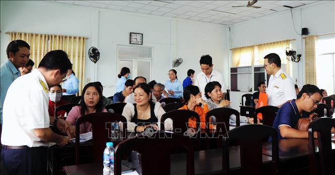 Cán bộ Thuế cơ sở 2 (Thuế thành phố Cần Thơ) giải đáp những vướng mắc của cá nhân, hộ kinh doanh phường Cái Răng trong quá trình thực hiện chính sách thuế mới liên quan đến hộ kinh doanh. Ảnh: Thu Hiền - TTXVN