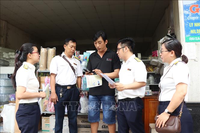 Cán bộ Thuế cơ sở 2 (Thuế thành phố Cần Thơ) đến tận nhà hướng dẫn giúp hộ kinh doanh phường Cái Răng tự kê khai doanh thu, tự đóng thuế. Ảnh: Thu Hiền - TTXVN
 