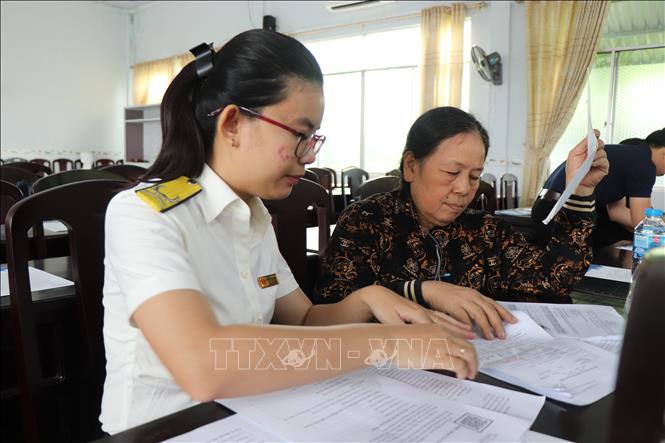 Hướng dẫn hộ kinh doanh phường Cái Răng chuyển đổi từ phương pháp thuế khoán sang kê khai thuế. Ảnh: Thu Hiền - TTXVN