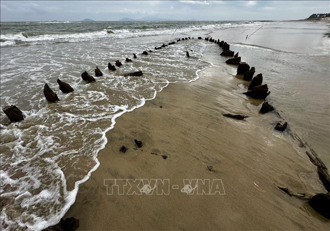 Con tàu lại bị ẩn dưới lớp cát biển mỗi khi thủy triều lên. Ảnh: Trần Lê Lâm - TTXVN