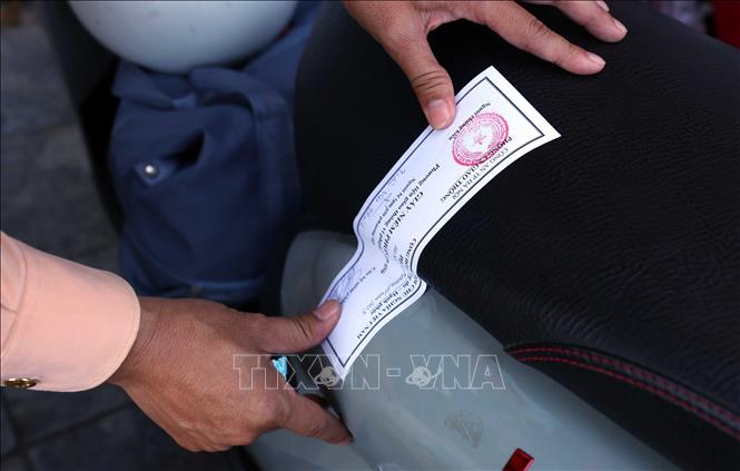 Đối với những trường hợp dán, che biển số xe không đủ giáy tờ (đăng ký xe, bằng lái xe) sẽ bị lực lượng chức năng lập biên bản xử phạt và tạm giữ phương tiện. Ảnh: Phạm Kiên - TTXVN