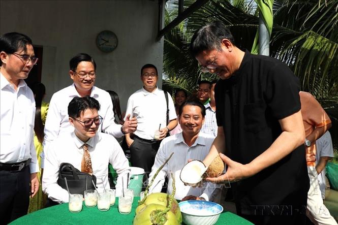  Ông Ngụy Hoa Tường, Tổng lãnh sự quán Trung Quốc tại Thành phố Hồ Chí Minh (áo đen) khen hương vị độc đáo của quả dừa sáp ở Trà Vinh. Ảnh: Thanh Hòa- TTXVN