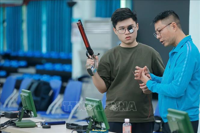 HLV Nguyễn Quốc Cường trao đổi với xạ thủ Lại Công Minh trong buổi tập. Ảnh: Minh Quyết - TTXVN