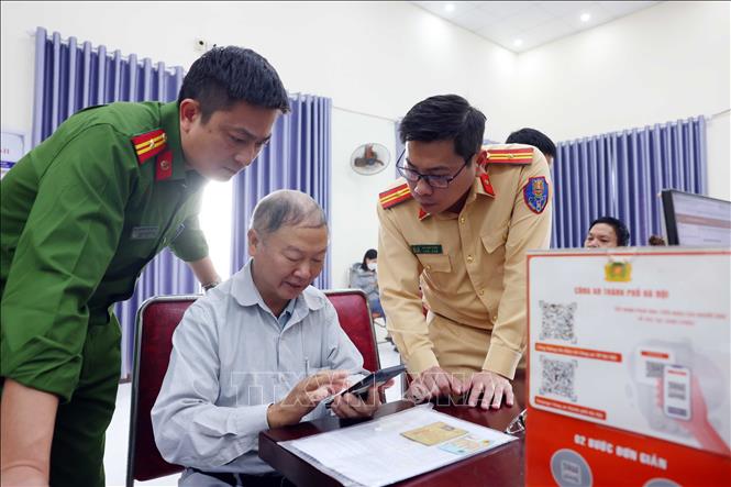 Phòng CSGT Hà Nội cử cán bộ Đội Đăng ký, quản lý phương tiện giao thông cơ giới đường bộ phối hợp cùng Công an xã Mê Linh triển khai tuyên truyền, hướng dẫn người dân sinh sống trên địa bàn thực hiện làm sạch dữ liệu đăng ký phương tiện, giấy phép lái xe. Ảnh: Phạm Kiên - TTXVN