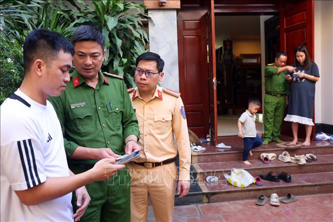 Cán bộ CSGT Hà Nội cùng với Công an xã Mê Linh đến nhà hướng dẫn cho người dân thực hiện làm sạch dữ liệu đăng ký phương tiện, giấy phép lái xe. Ảnh: Phạm Kiên - TTXVN