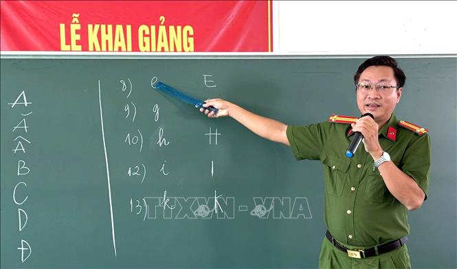 Công an hướng dẫn học viên nhận biết mặt chữ cái. Ảnh: Văn Sĩ - TTXVN