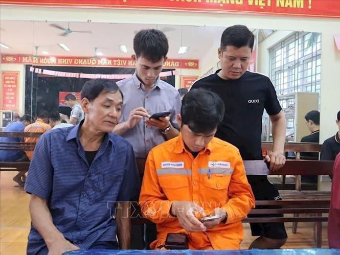Nhân viên EVNHANOI hướng dẫn khách hàng tai Nhà văn hóa Cụm 9 xã Ô Diên, thành phố Hà Nội. Ảnh: Quốc Lũy - TTXVN