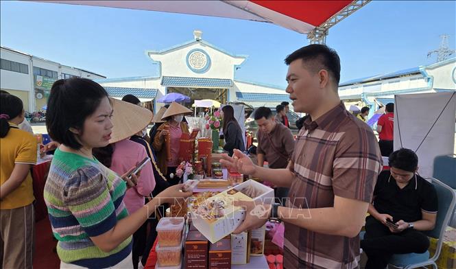 Tiểu thương Nguyễn Huy Lợi giới thiệu sản phẩm với khách hàng. Ảnh: Minh Thu- TTXVN