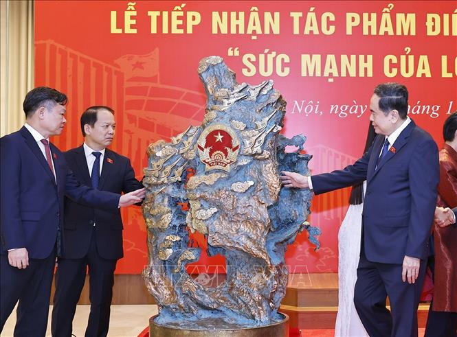  Chủ tịch Quốc hội Trần Thanh Mẫn và đại biểu với nghệ nhân tại Lễ tiếp nhận tác phẩm điêu khắc ánh sáng. Ảnh: Doãn Tấn - TTXVN