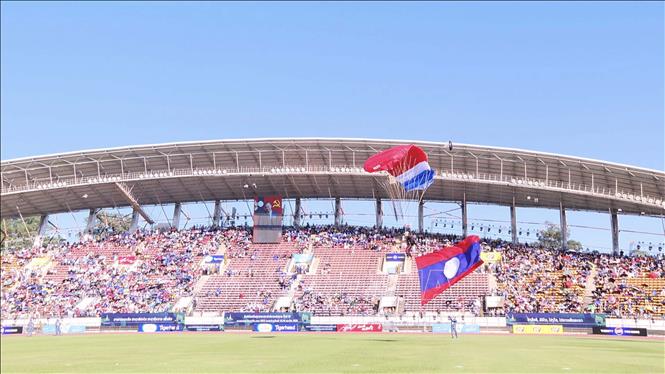 Màn nhảy dù từ độ cao 2.000m xuống sân vận động quốc gia ở thủ đô Viêng Chăn (Lào) của 1 chiến sĩ mang theo cờ Tổ quốc Lào tại lễ khai mạc. Ảnh: Đỗ Bá Thành - PV TTXVN tại Lào